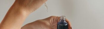 Woman applying facial serum from a dropper bottle, step in a personalized skincare routine for glowing skin.